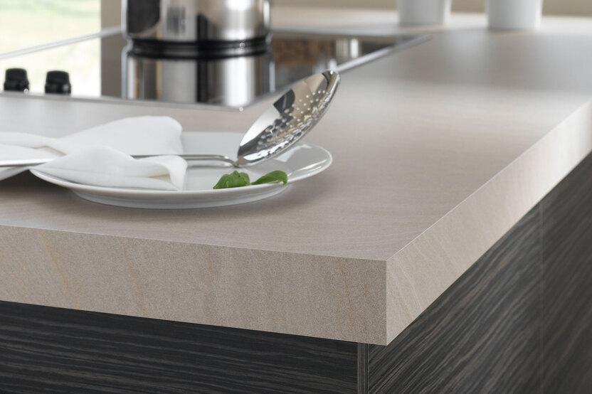 Detailaufnahme einer Küchenzeile mit Kochfeld und verschiedenen Oberflächen Detailaufnahme einer Küchenzeile mit Kochfeld und heller Arbeitsplatte in Steinoptik und dunkler Schrankverkleidung