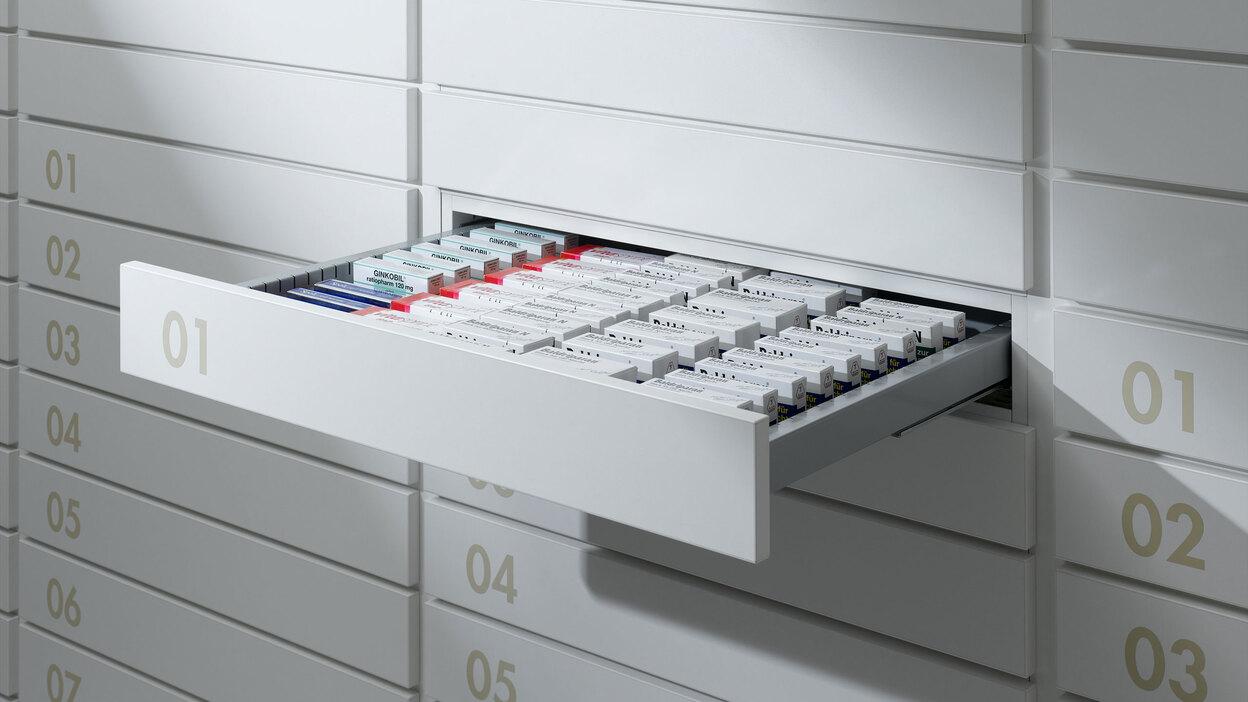 Detailaufnahme von schmalen weißen Medikamentenschubläden mit dezenter Nummerierung und sichtbarer Medikamentenaufteilungen.