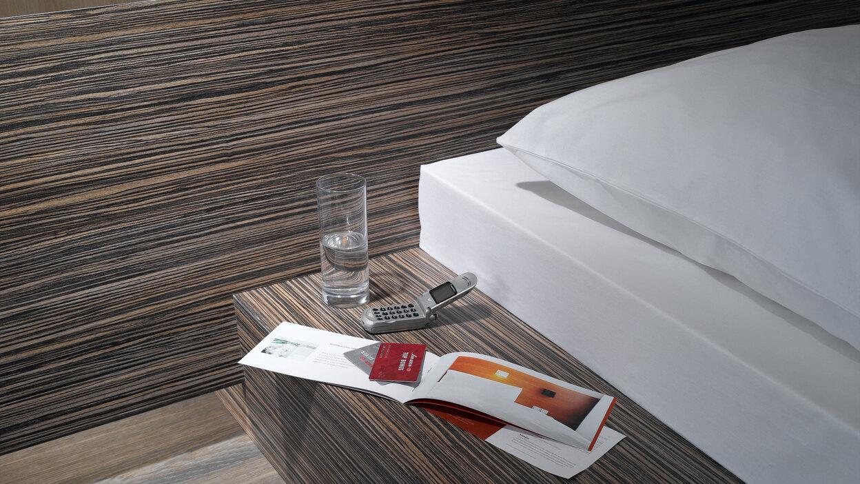 Detailaufnahme von Bettumrandung in dunklem Holz mit Ablagemöglichkeit