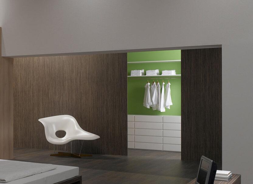 Schlafzimmerimpression mit Holzverkleidung an Wand Schlafzimmerimpression von Bett, Nachtisch und Sideboard mit Holzverkleidung an Wand und indirektert Beleuchtung