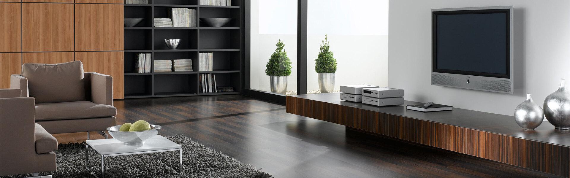 Wohnraumimpression mit verschieden dunklen Holzoberflächen für Einbauschrank, Sideboard und Bodenbelag