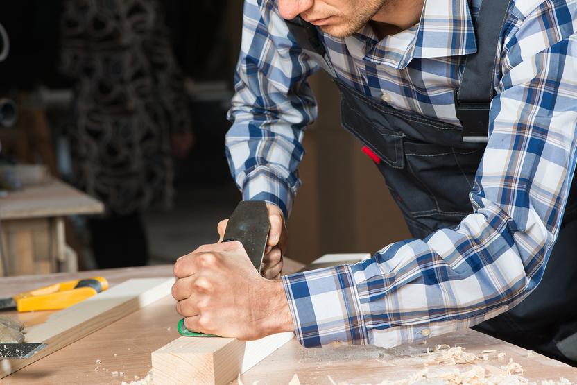 Tischler mit Handhobel in seiner Werkstatt Tischler mit Handhobel in seiner Werkstatt